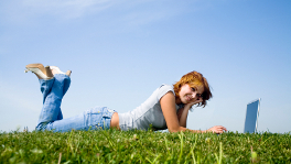 Girl with laptop lying on grass